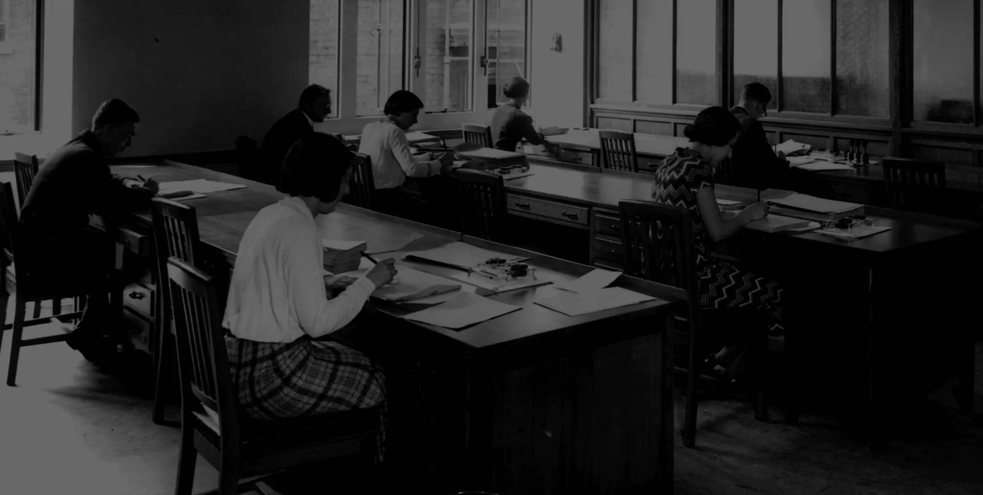 Black and white photo of people working on desks